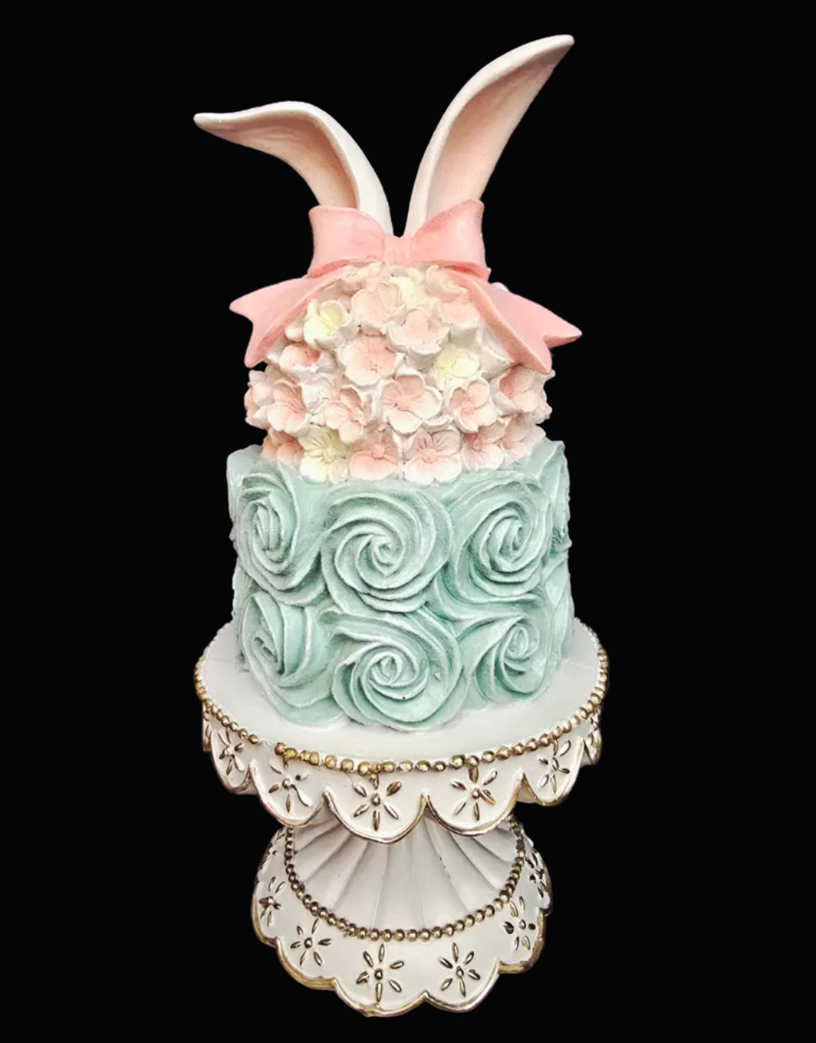 Faux two-tier Easter cake decoration with mint rosette swirls, blush cherry blossom detail, pink bow and cream bunny ears on white and gold scalloped stand, on black background — 35cm high — Mistletoe Home