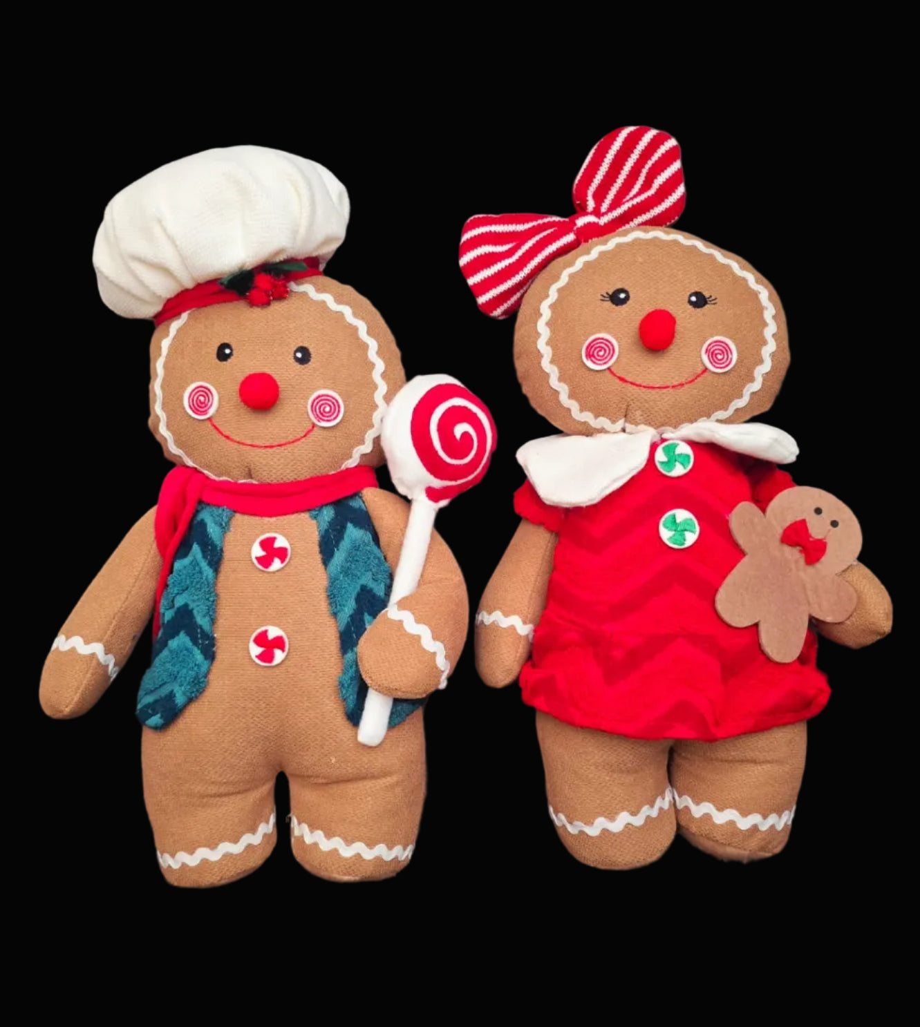 Gingerella Boy and Girl plush gingerbread decorations side by side on black background — boy with chef's hat, teal vest and lollipop; girl with red striped bow, red dress and mini gingerbread toy — Mistletoe Home