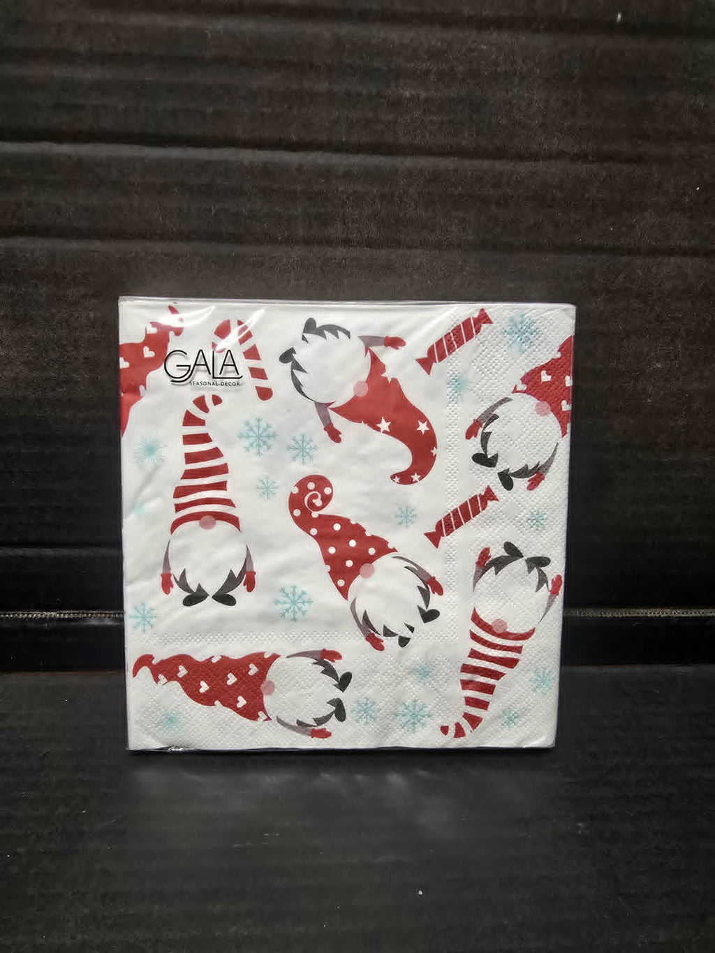 Pack of 20 white paper napkins with red Christmas gnome and blue snowflake print by Gala in clear packaging on dark background — Mistletoe Home