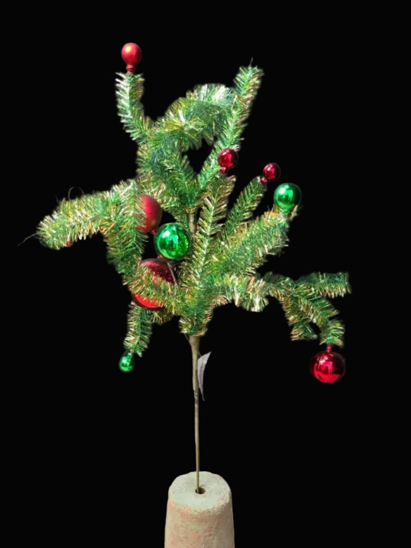 Small artificial Christmas spray with decorations on a plain background