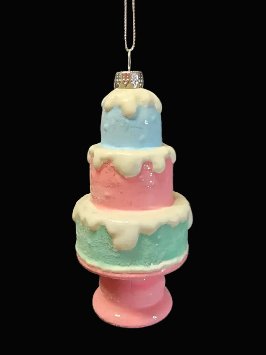 Pastel-colored three-tiered cake ornament on a dark background