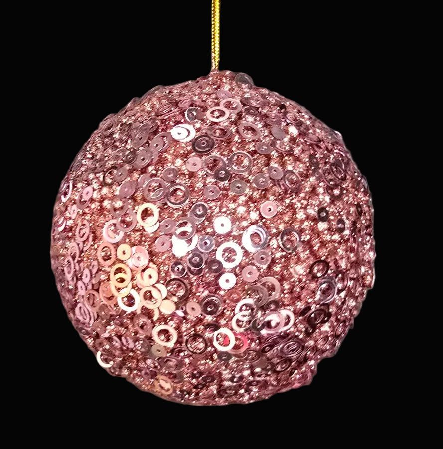 Rose gold sequin ball hanging against a dark background