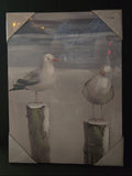 Two seagulls on wooden posts with a blurred background