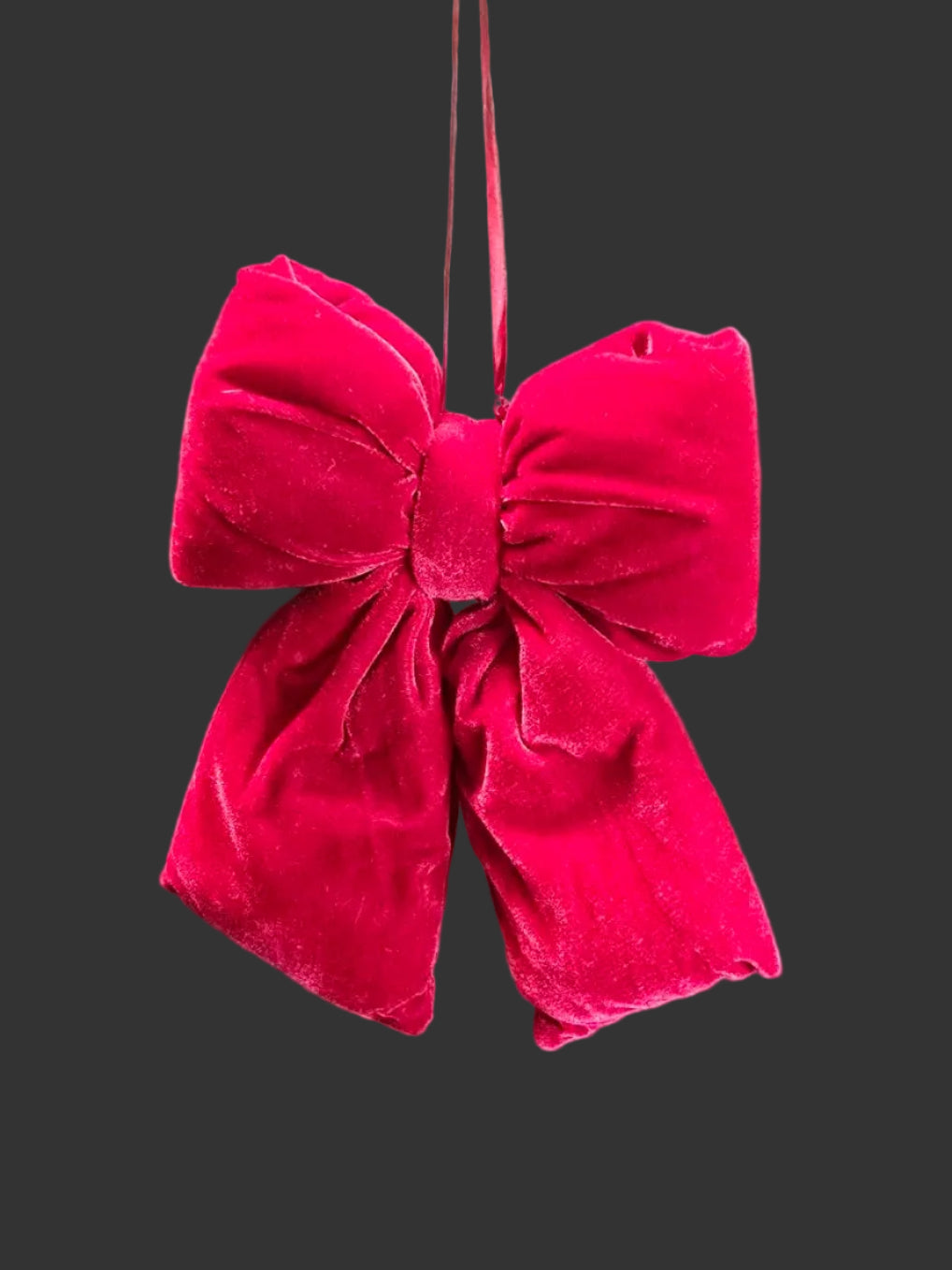 Red velvet bow hanging against a black background