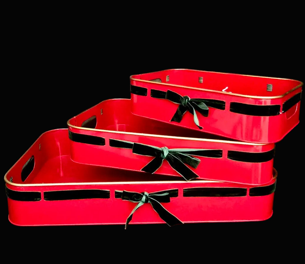 Set of three red metal trays with green ribbons on a black background