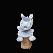 Plush toy capybara on a wooden stand against a black background