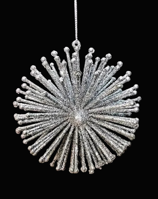 Decorative silver ornament hanging against a dark background