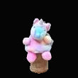 Small plush toy on a cone with colorful decorations against a black background