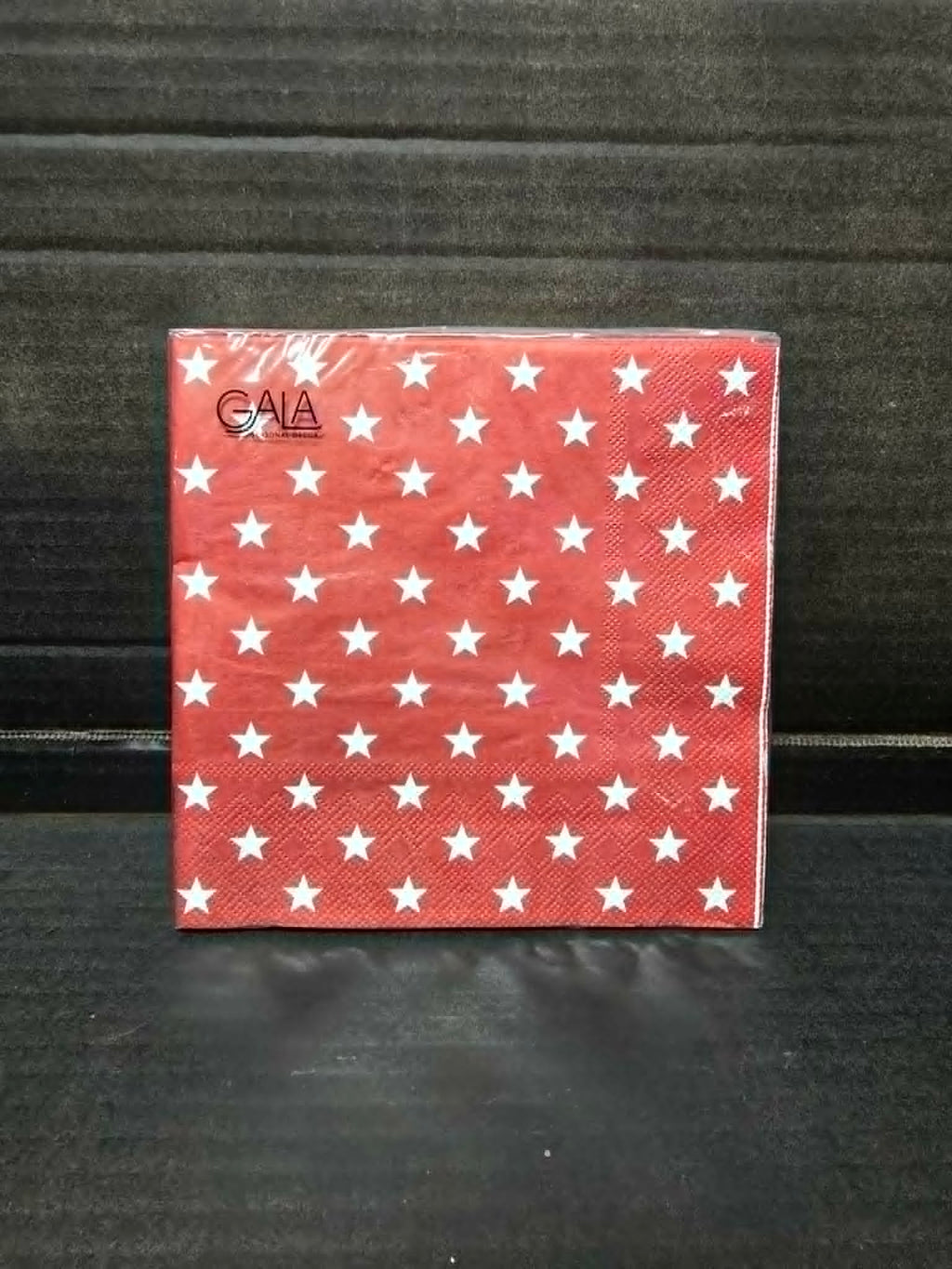 Pack of 20 red and white star print Gala paper napkins in clear packaging on dark background — Mistletoe Home