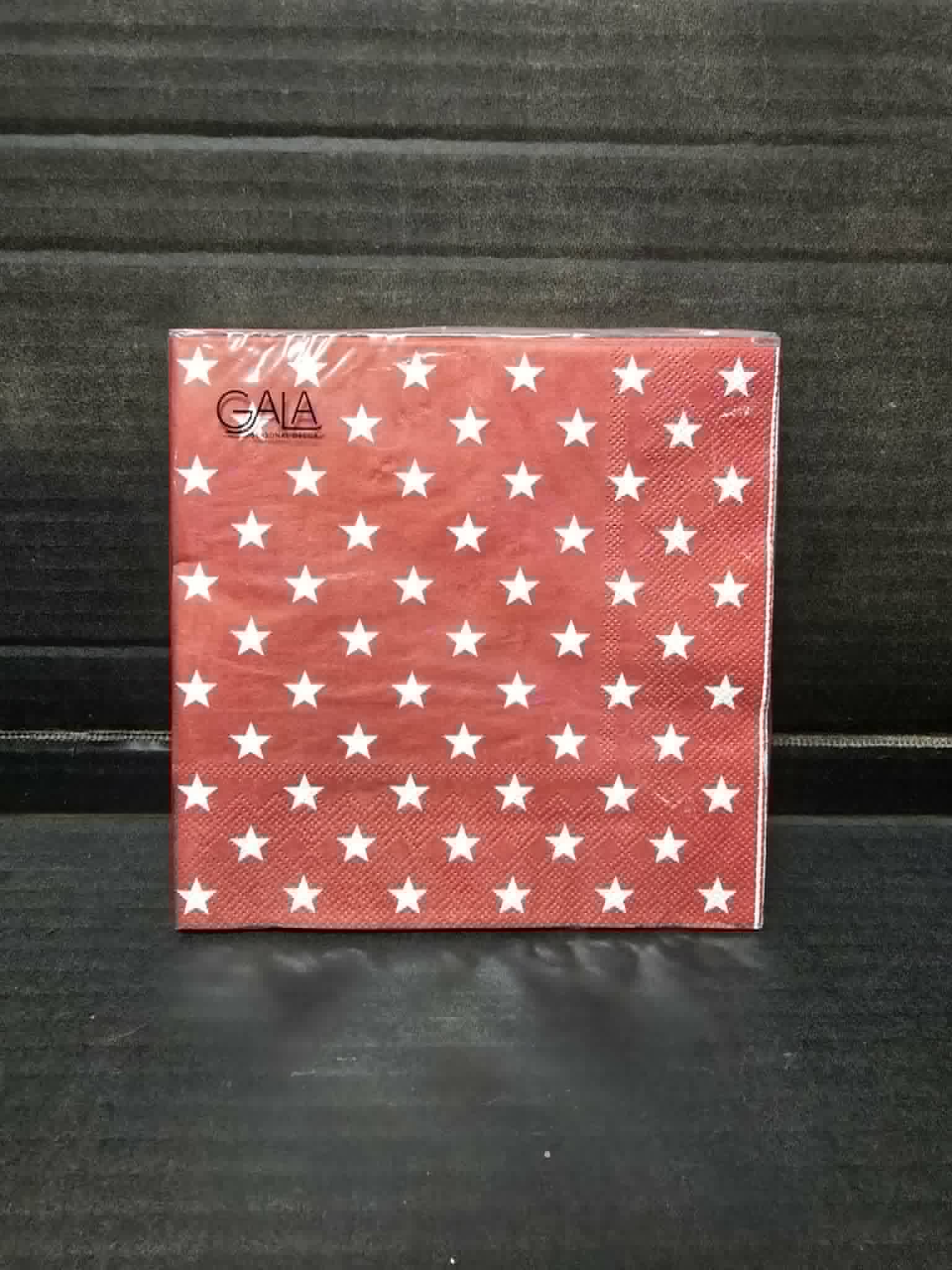 Pack of 20 red and white star print Gala paper napkins in clear packaging on dark background — Mistletoe Home